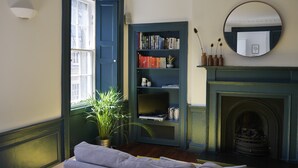 A room with a bookshelf, a fireplace, a mirror, and a window. - fantastic 2 bedroom on a bohemian street in Edinburgh's New Town (Edinburgh)