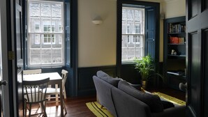 A room with a sofa, a dining table with chairs, and a bookshelf. - fantastic 2 bedroom on a bohemian street in Edinburgh's New Town (Edinburgh)