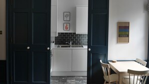 A modern kitchen with white cabinets, a black backsplash, and a dining area with a table and chairs. - fantastic 2 bedroom on a bohemian street in Edinburgh's New Town (Edinburgh)