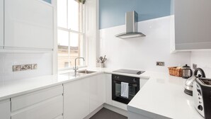 A modern kitchen with white cabinets, a built-in oven, a stainless steel range hood, and a window with a view of the outside. - Incredible 1 bedroom + sofabed on the famous Royal Mile 200 metres from Edinburgh Castle (Edinburgh)