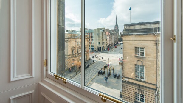A view from a window of a city street with historic buildings, a church spire, and a clear sky. - Incredible 1 bedroom + sofabed on the famous Royal Mile 200 metres from Edinburgh Castle (Edinburgh)