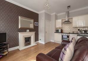 A living room with a fireplace, a television, and a leather sofa.