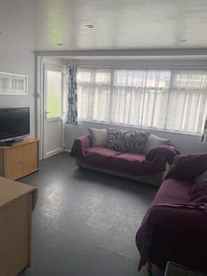 Relax in this inviting living room with a sofa, TV, and large window.