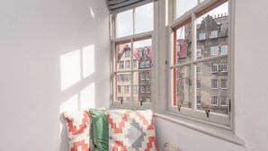 A corner with a window, a fur rug, and two patterned pillows.