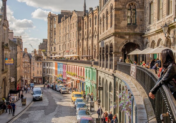 A cobblestone street lined with historic buildings, a pedestrian bridge, and outdoor seating areas. - Wonderful 1 bedroom + sofabed in the heart of the Old Town (Edinburgh)