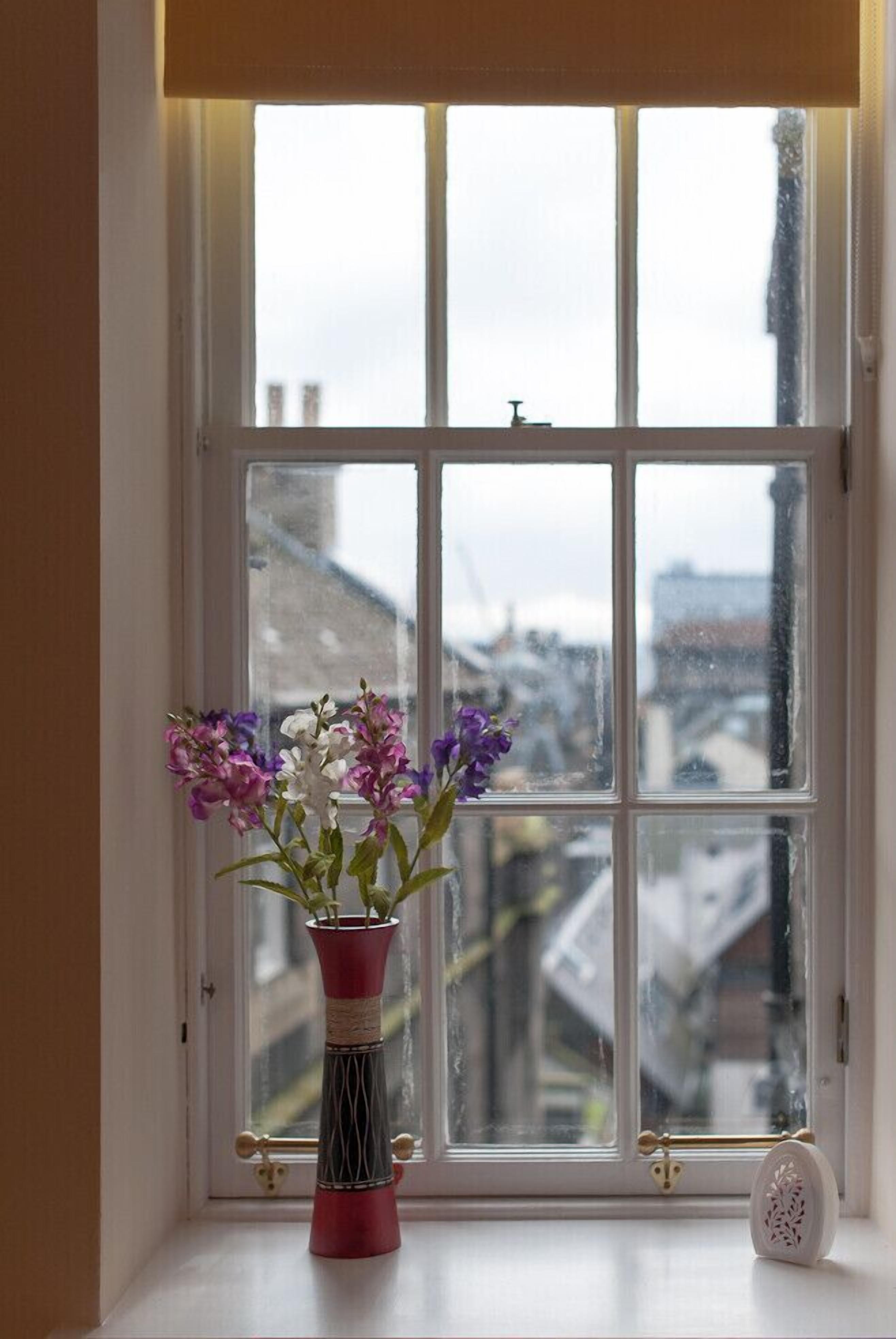 A window with a vase of flowers on a windowsill.
