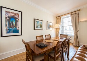 Un comedor con una mesa de madera, seis sillas y cuadros en la pared.