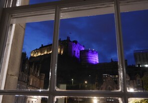 A historic building with a prominent tower and a round structure, viewed through a window at night.