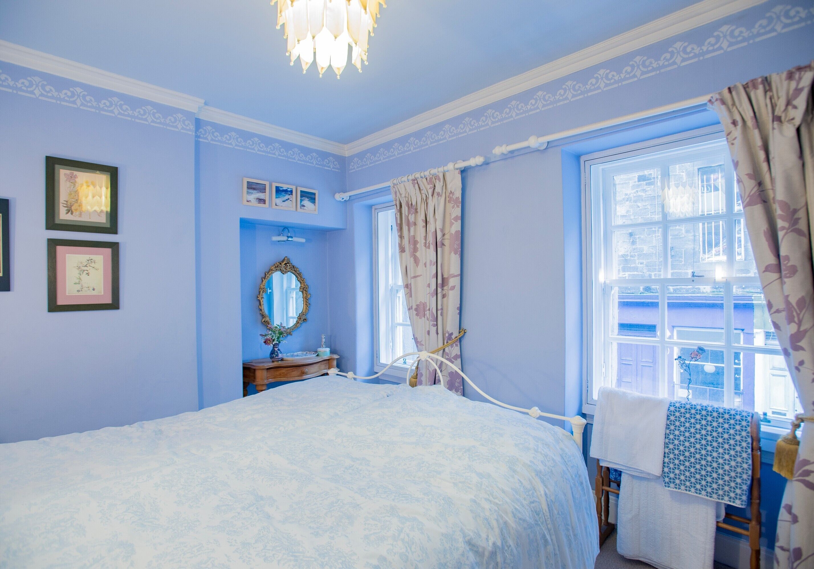A bedroom with a bed, a dresser, a mirror, and a window with curtains.