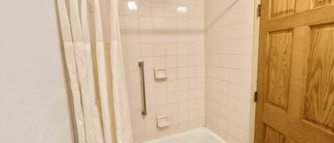 Un baño con ducha, bañera y puerta de madera.