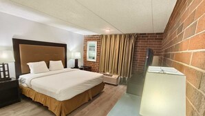 A hotel room with a bed, bedside tables, a lamp, a heater, and a brick wall.
