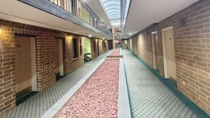A hotel corridor with brick walls, a central walkway, and a skylight.