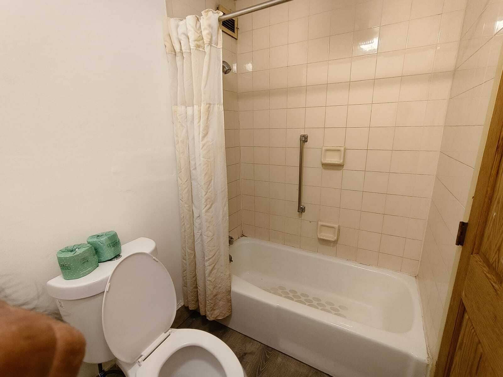 Un baño con inodoro, ducha con cortina y bañera.