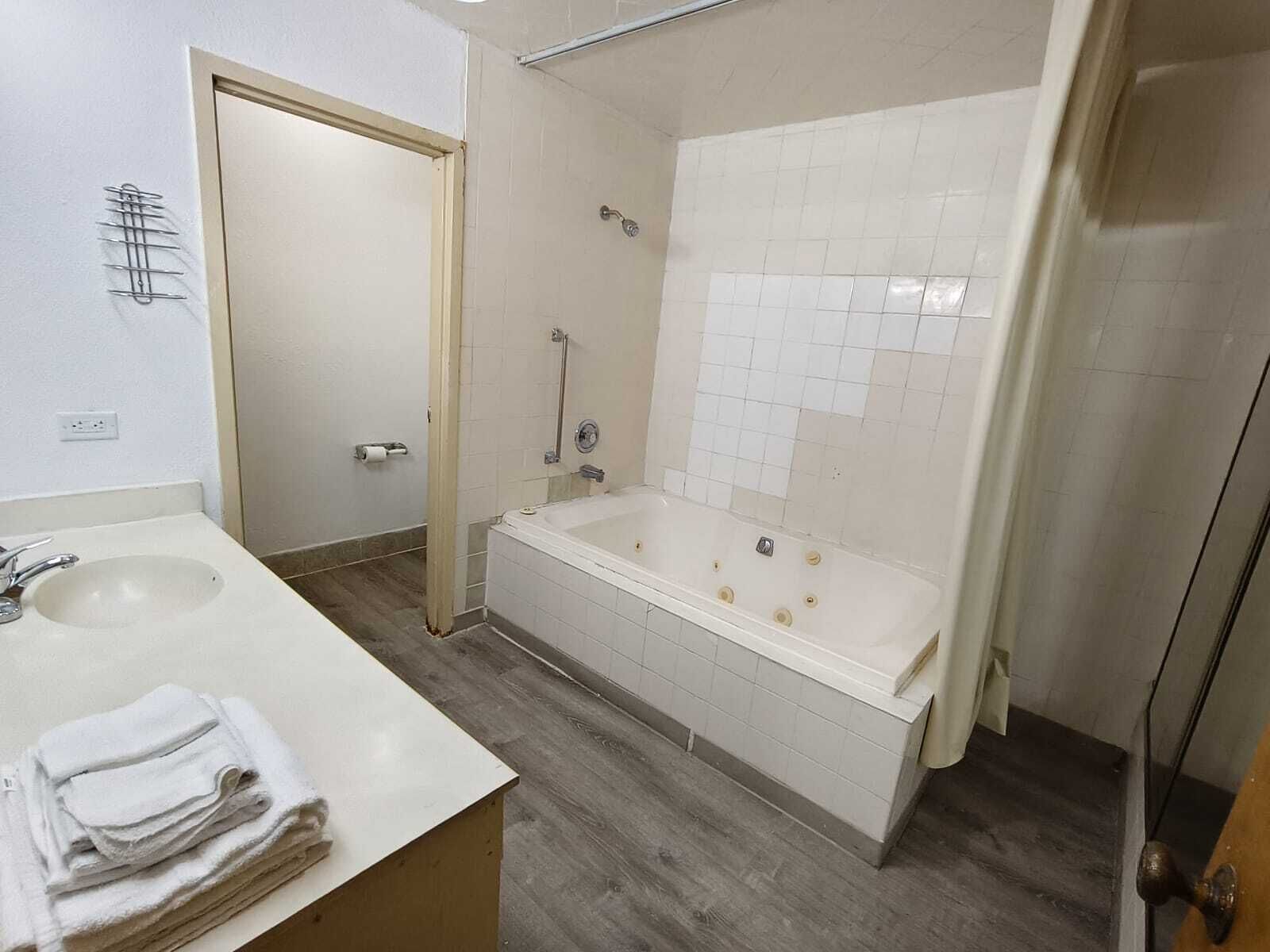 Et badeværelse med håndvask, badekar og bruseniche.