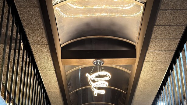 A modern interior with a central spiral light fixture, metal railings, and a brick wall.