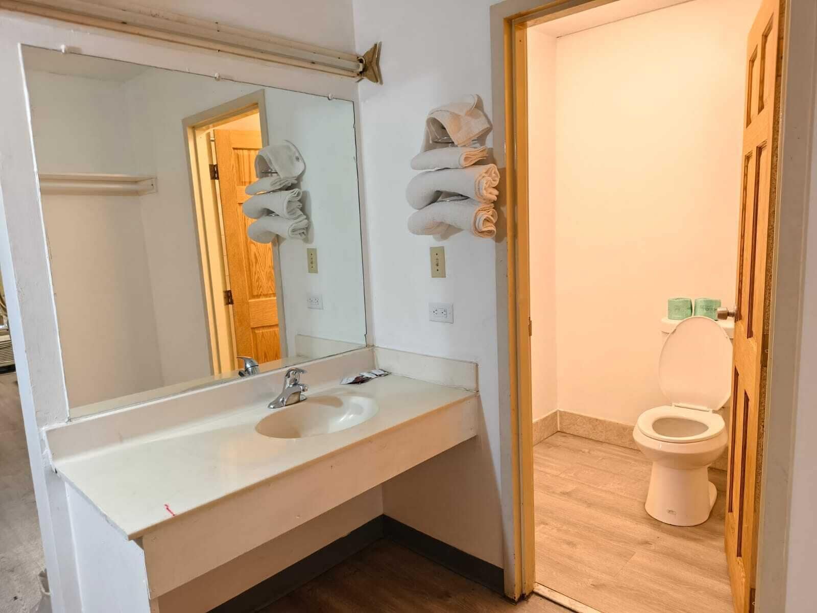 A bathroom with a sink, mirror, towel rack, and toilet.
