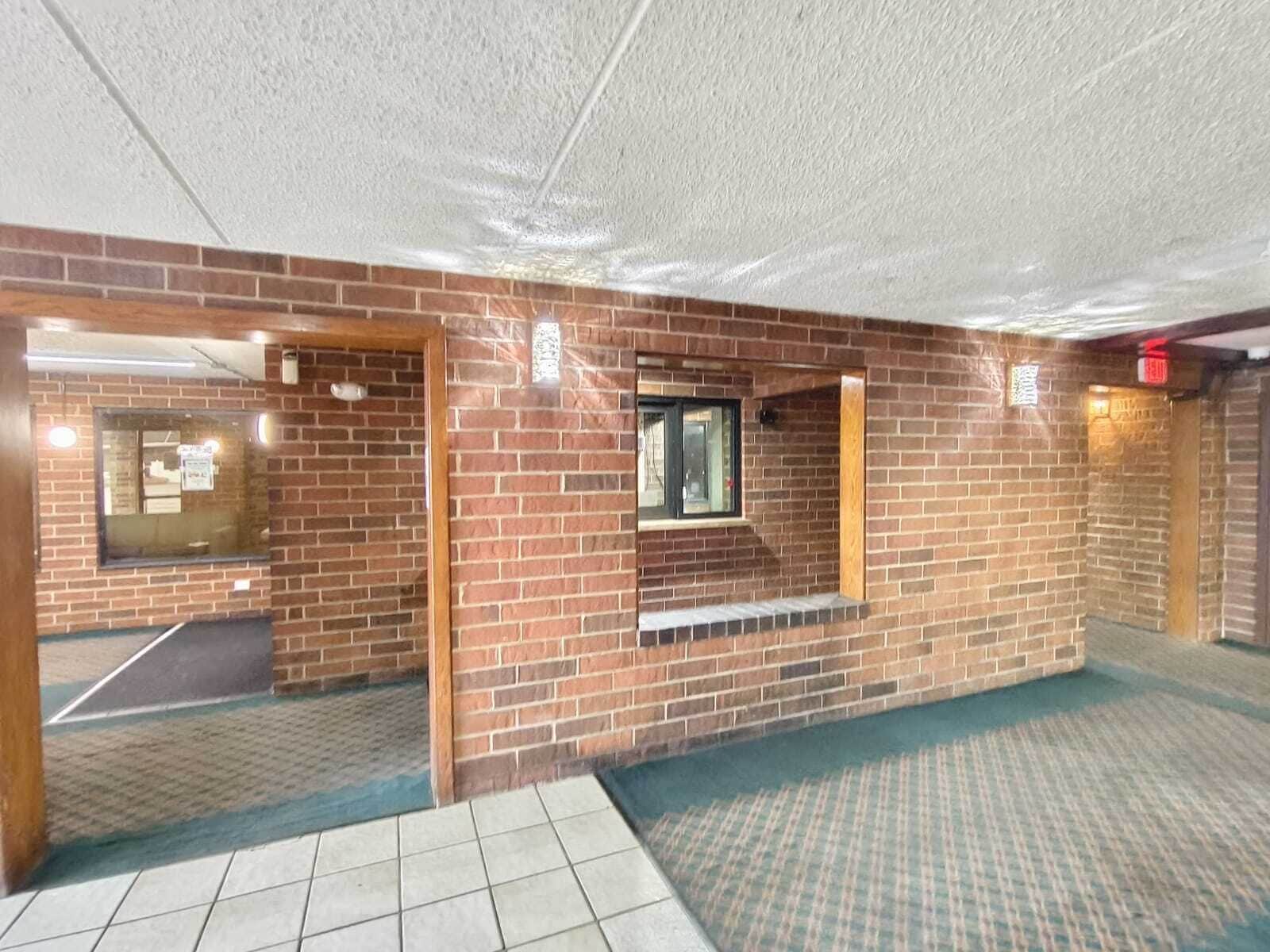 A brick-walled room with a window, a door, and a tiled floor.