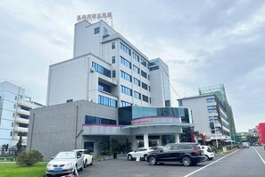 A multi-story building with a parking lot in front. - Yulin Hotel (Yuchai Shop) (Yulin)