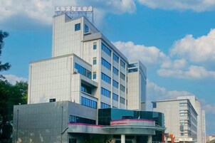 Un edificio de varios pisos con un diseño arquitectónico moderno, que destaca por una entrada con fachada curva y techo plano.