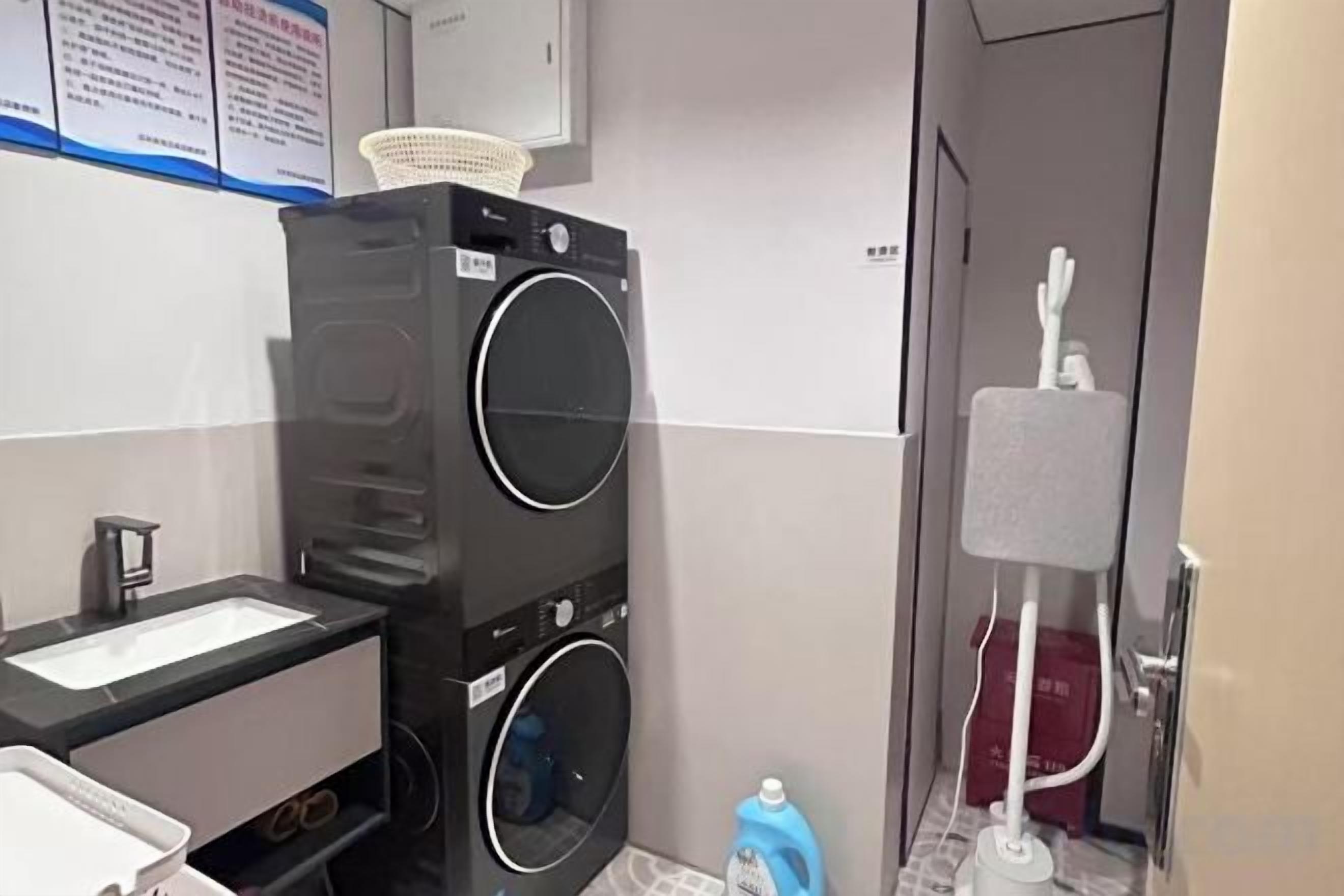 Une chambre d’hôtel de taille réduite, équipée d’une machine à laver, d’un petit lavabo et d’un miroir.