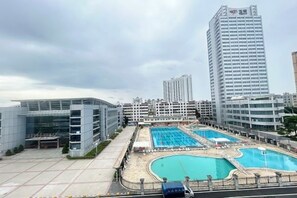 A modern hotel with multiple floors, a swimming pool, and a parking area. - Yulin Hotel (Yuchai Shop) (Yulin)