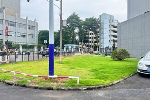 A grassy area with a blue pole, a white fence, and a car parked nearby. - Yulin Hotel (Yuchai Shop) (Yulin)