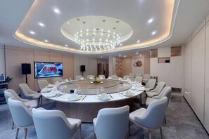 A conference room with a round table, chairs, a large chandelier, and a television screen. - Yulin Hotel (Yuchai Shop) (Yulin)