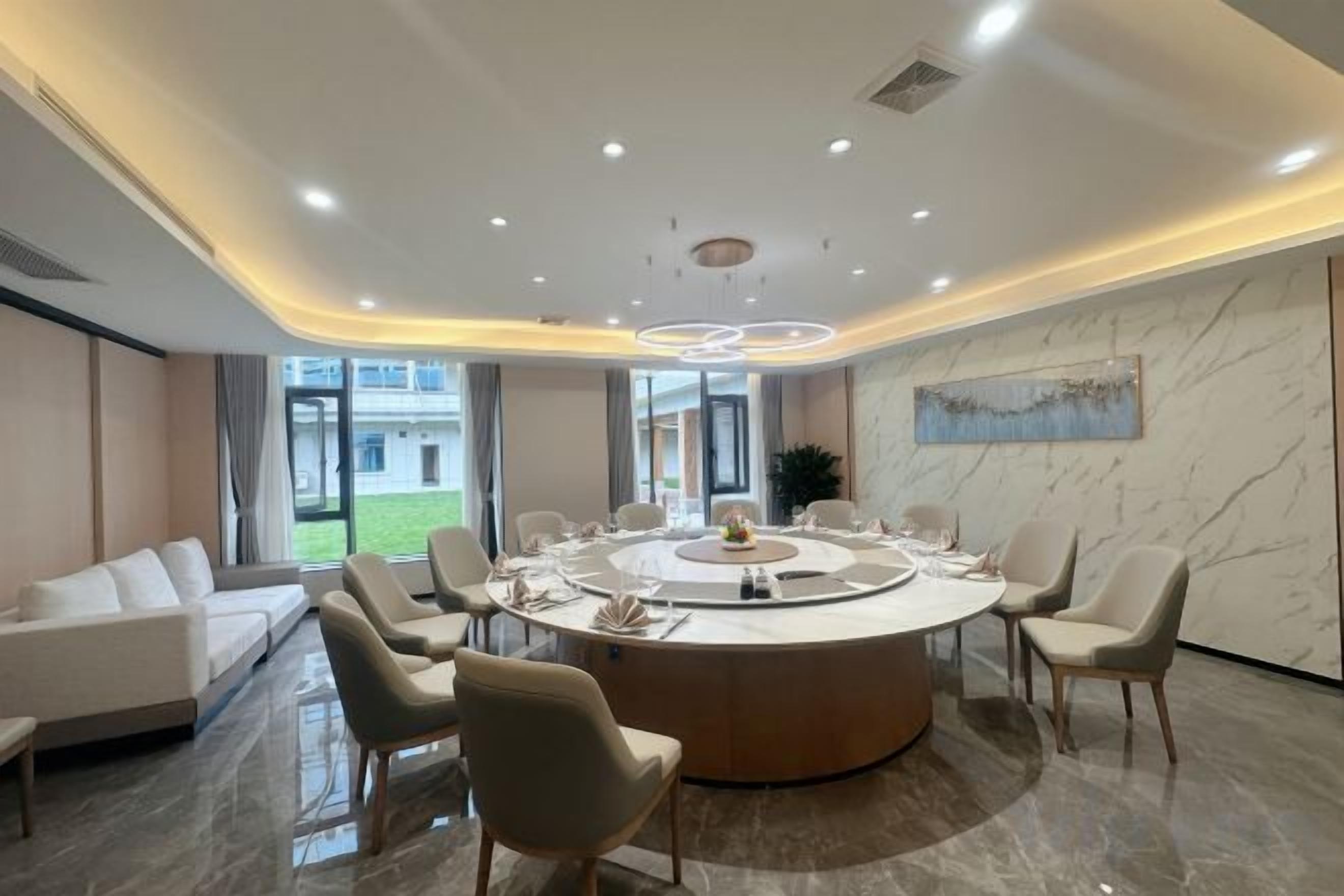 A modern conference room with a round table, chairs, and a sofa.