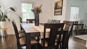 Un comedor con una mesa y sillas de madera, un florero con flores y obras de arte en las paredes.