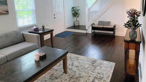 Una sala de estar con sofá, una mesa de centro y una escalera que sube a otro nivel.