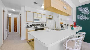 Une cuisine moderne avec des meubles blancs, un îlot central et un mur d’accent vert.