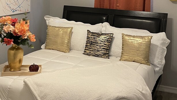 A bedroom with a bed, a clock, a ceiling fan, and a wall art piece. - Beautiful Gated private home (Houston)