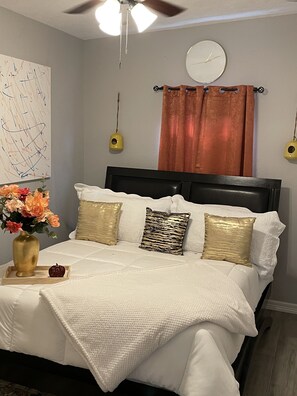 A bedroom with a bed, a clock, a ceiling fan, and a wall art piece. - Beautiful Gated private home (Houston)