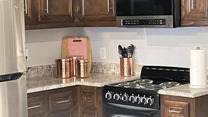 A kitchen with dark wooden cabinets, stainless steel appliances, a microwave, a toaster, and a stove. - Beautiful Gated private home (Houston)