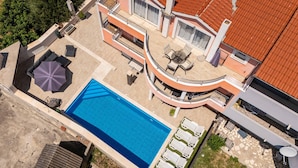 Un edificio a più piani con piscina, area salotto all'aperto e tetto in tegole rosse.