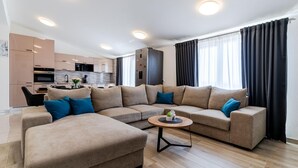 A modern living room with a sectional sofa, a small coffee table, and a kitchen in the background. - Beach front apartment in Solin (Solin)