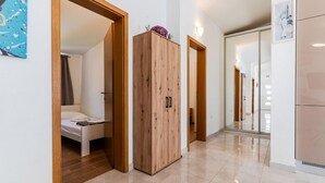 Corridoio di un hotel con porte in legno, un letto e un bagno con specchio e WC.