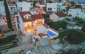 Ein zweistöckiges Haus mit Swimmingpool, Steinmauern und einem begrenzten Eingangsbereich.