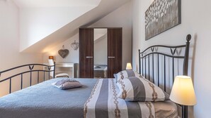Une chambre à coucher comprenant un lit, des lampes de chevet, un bureau et une armoire.