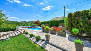 Un jardin avec une piscine, des chaises longues et des plantes en pot.