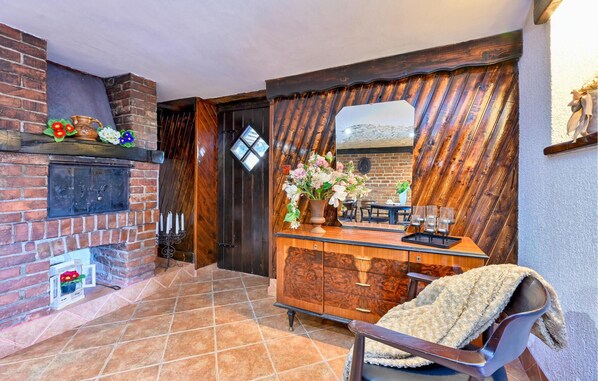 Un interior acogedor con chimenea, un aparador de madera y un sillón cómodo.