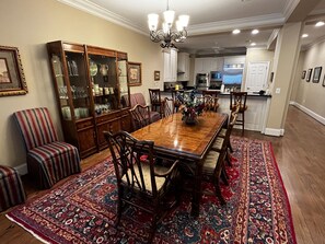 Un vaste espace dédié à la salle à manger, avec une grande table en bois entourée de chaises, un tapis à motifs et un buffet pour la vaisselle.
