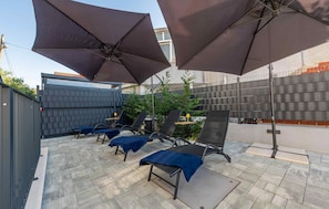 A patio with outdoor seating, umbrellas, and a tiled floor.