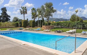 Une piscine rectangulaire avec un mur en pierre et une rambarde en métal.