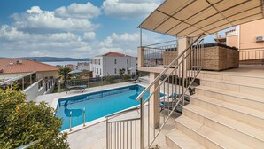 A pool area with a clear view of the sea, a staircase leading to a balcony, and a covered seating area. - Nice home in Okrug Gornji with sauna (Okrug Gornji)