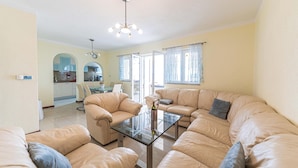 A living room with a glass coffee table, beige sofas, and a dining area with a glass table. - Nice home in Okrug Gornji with sauna (Okrug Gornji)