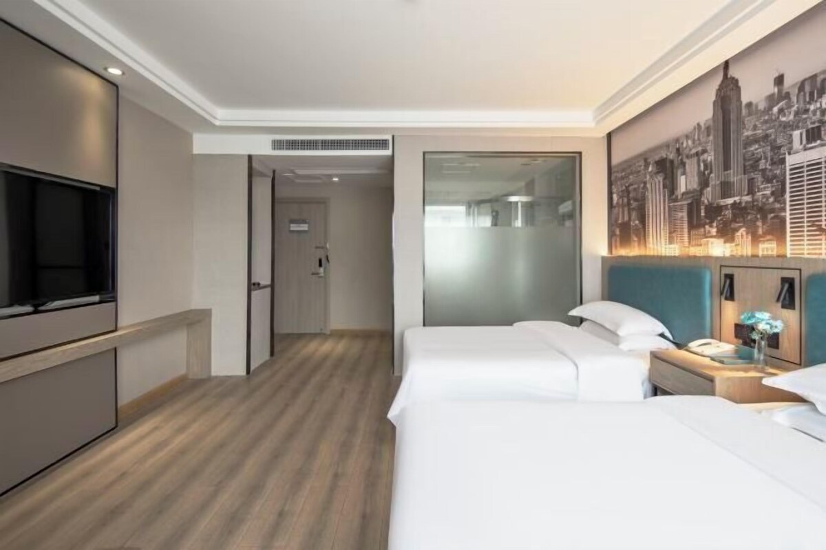 Une chambre d’hôtel avec un grand lit, une télévision, une fresque représentant un paysage urbain et un plancher en bois.