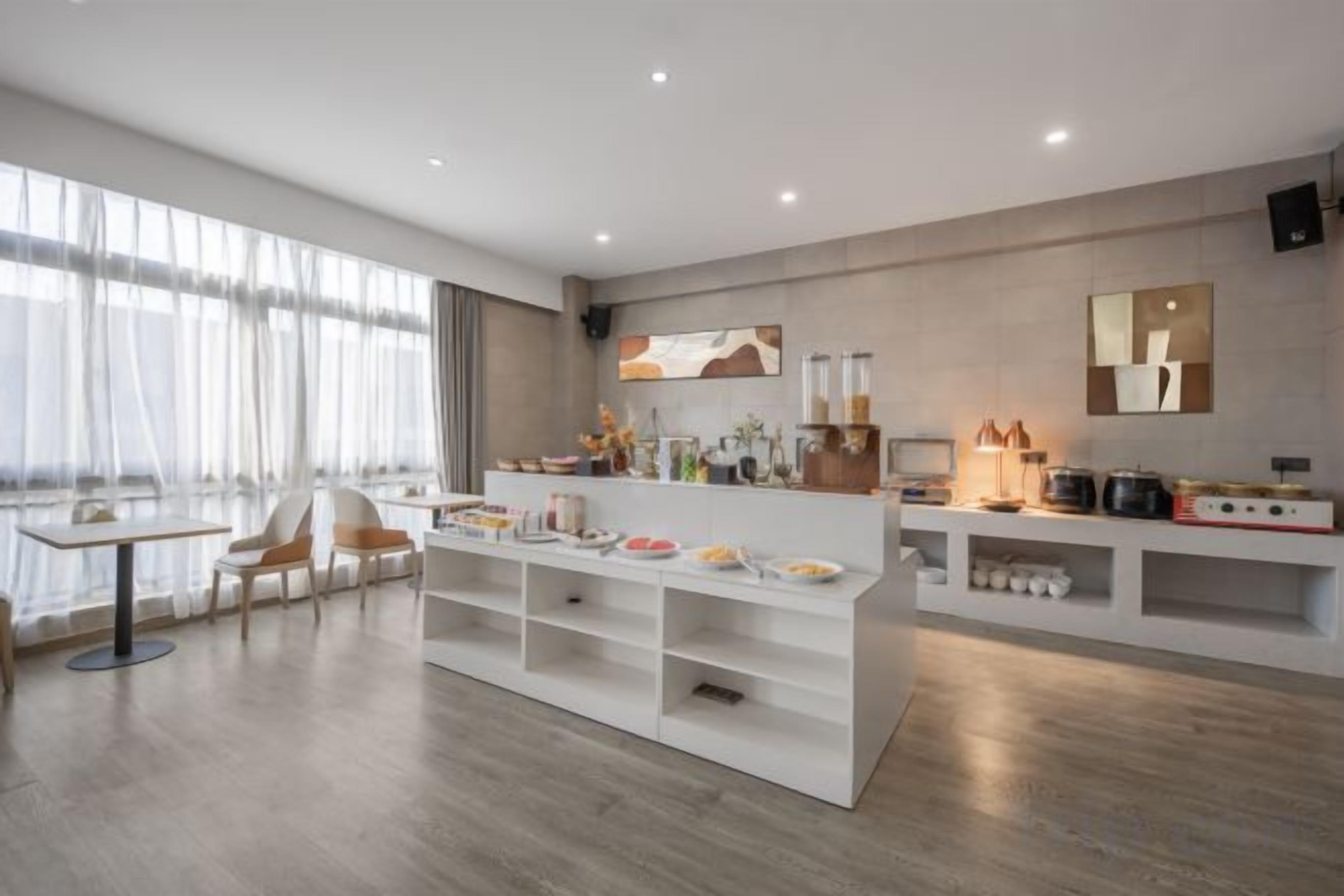 A modern kitchen with a central island, white cabinetry, and a dining area with chairs.