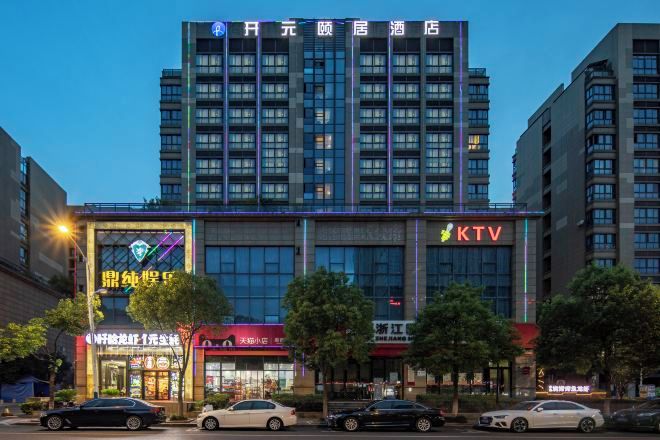 A multi-story hotel building with a prominent KTV sign, a visible entrance, and several cars parked in front.