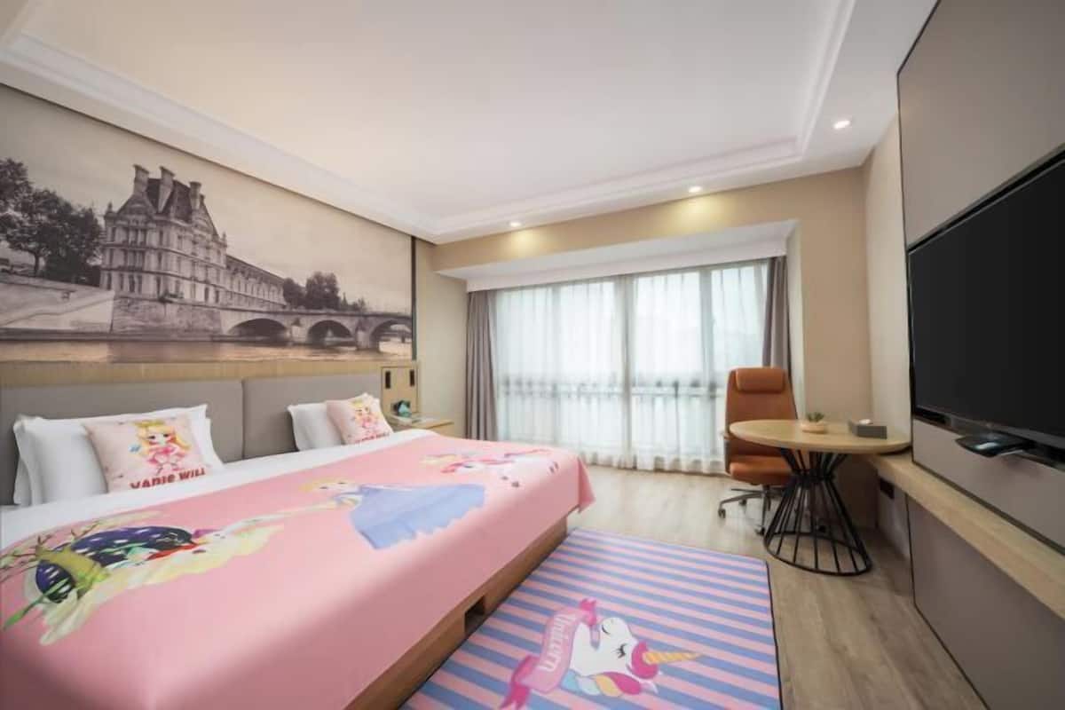 Ein Hotelzimmer mit Bett, Fernseher, Fenster mit Vorhängen und einem Bild einer Brücke.